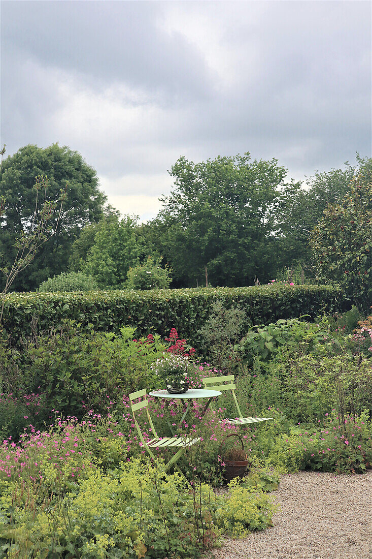 Small garden seating area between flowering perennials in the summer garden