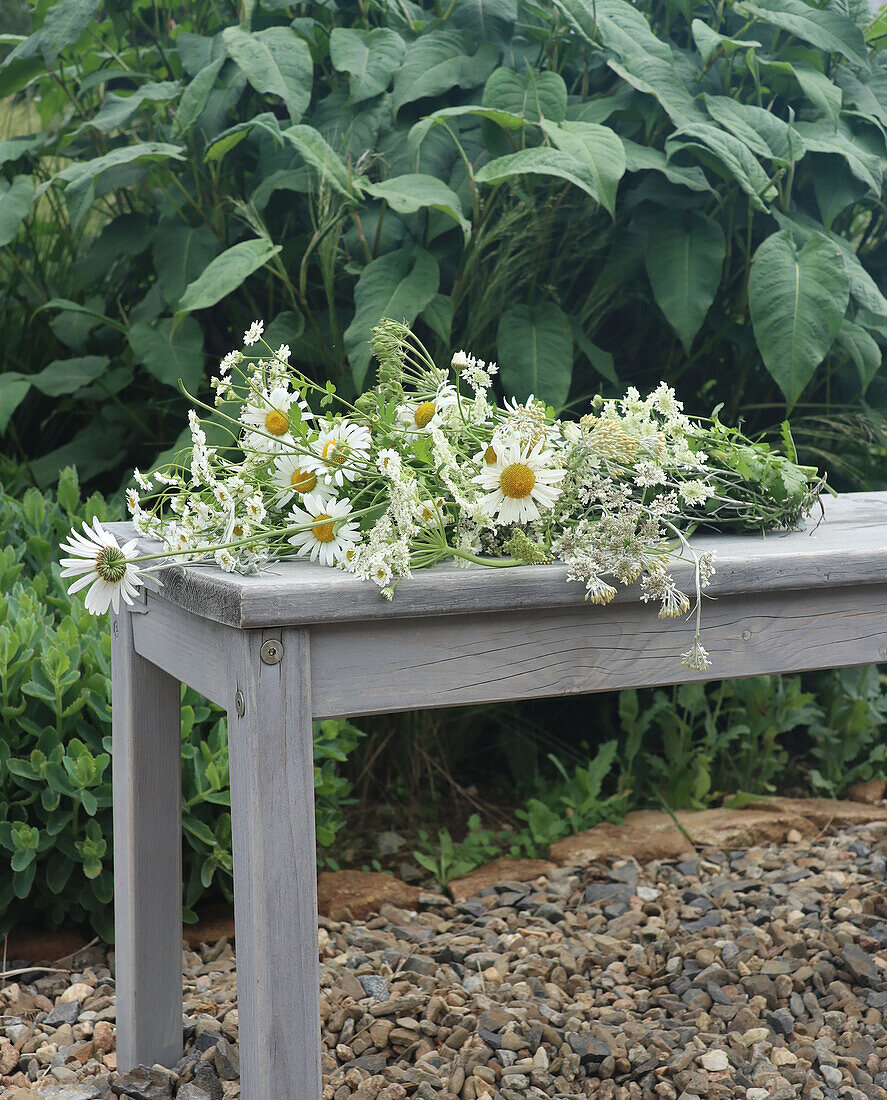 Wildflower bouquet with chamomile on a grey wooden garden bench