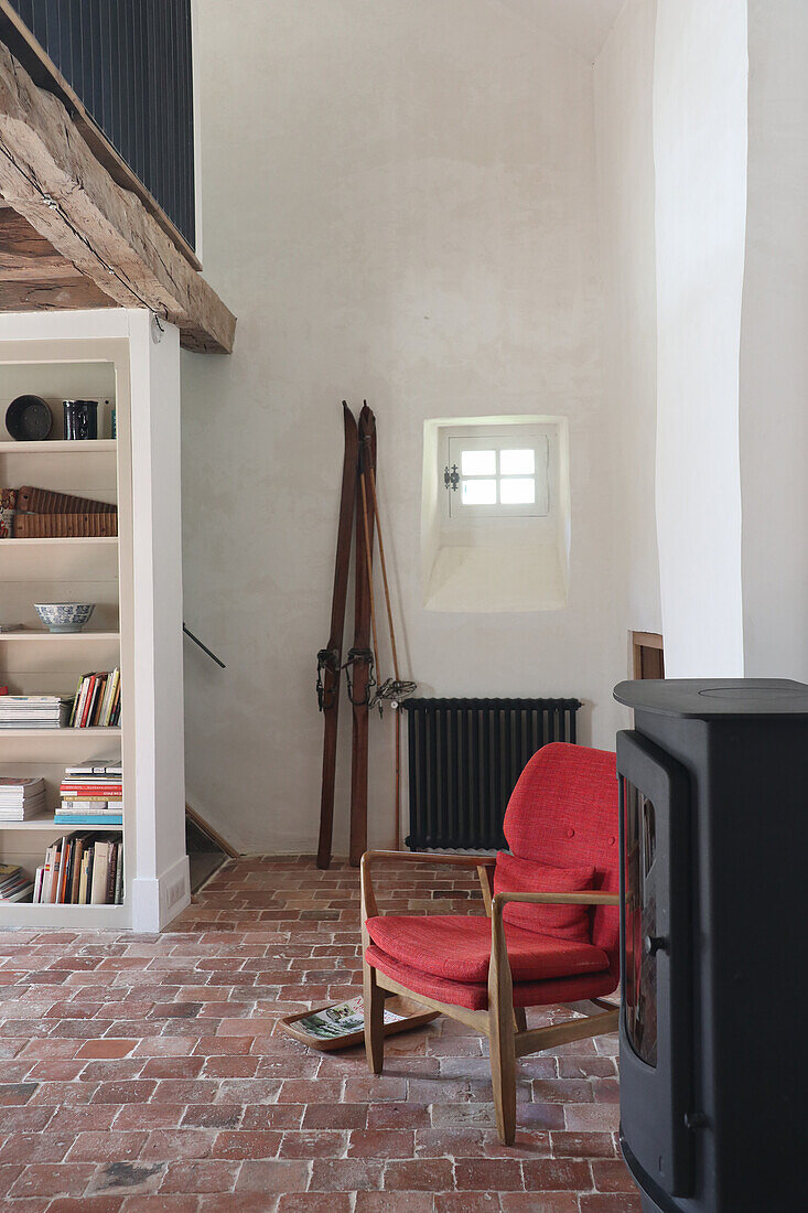 Red retro armchair in front of fireplace in rustic living room