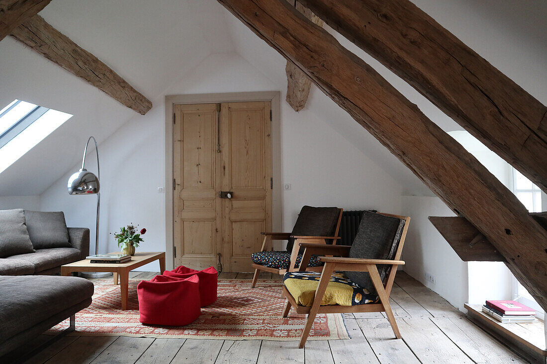 Wohnzimmer im Dachgeschoss mit Holzbalken und Vintage-Sesseln