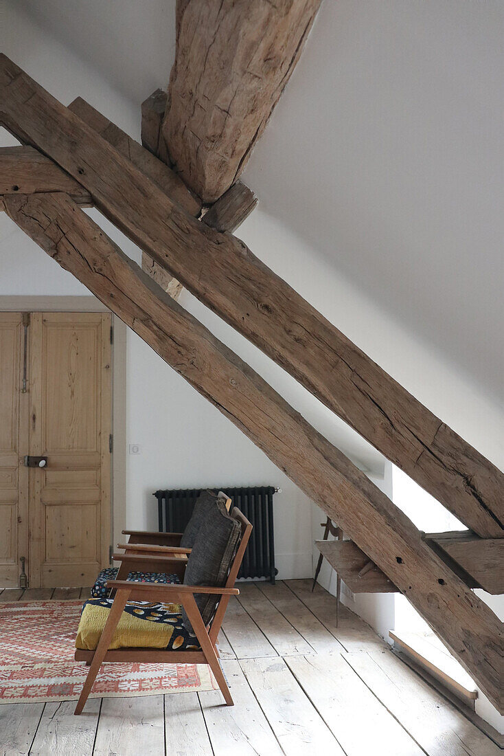 Retro armchair under wooden beams in modern attic room