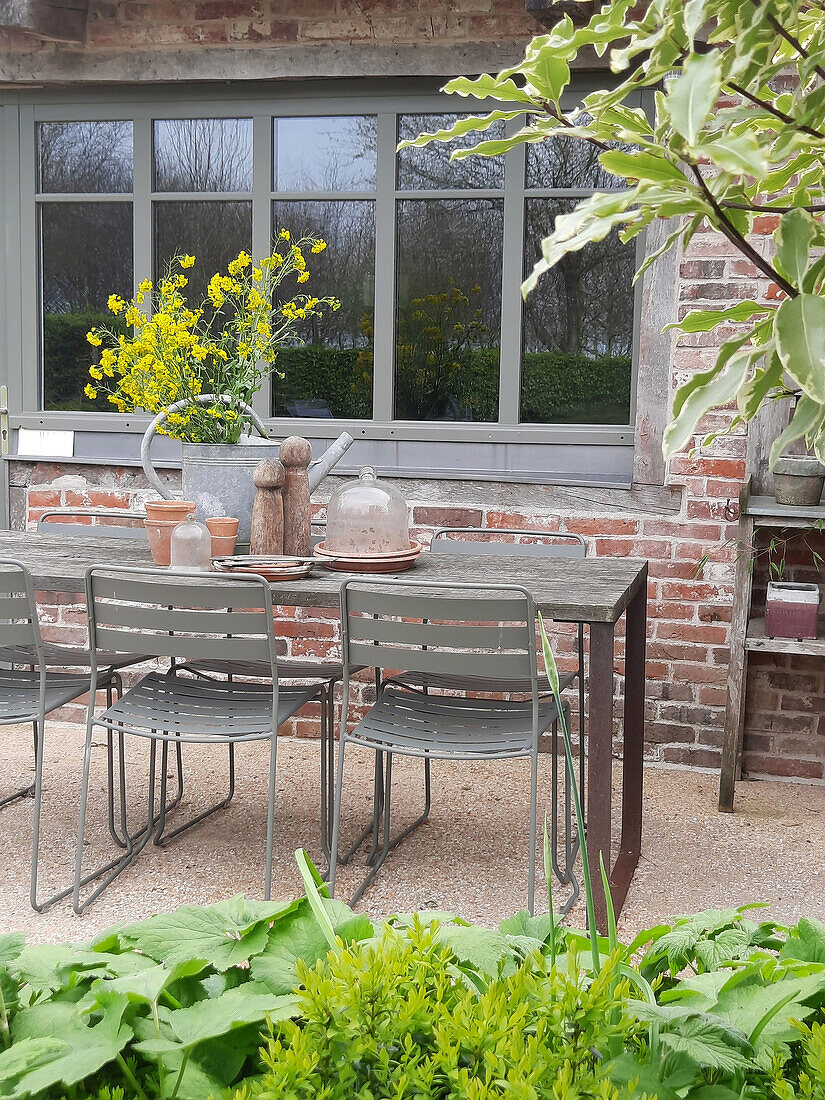 Gartenbereich mit Tisch, Stühlen und Blumen in Gießkanne