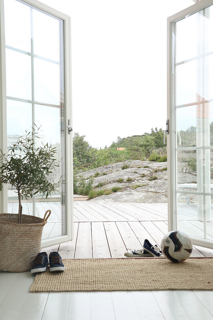 Open patio doors with a view of a wooden terrace and rocks