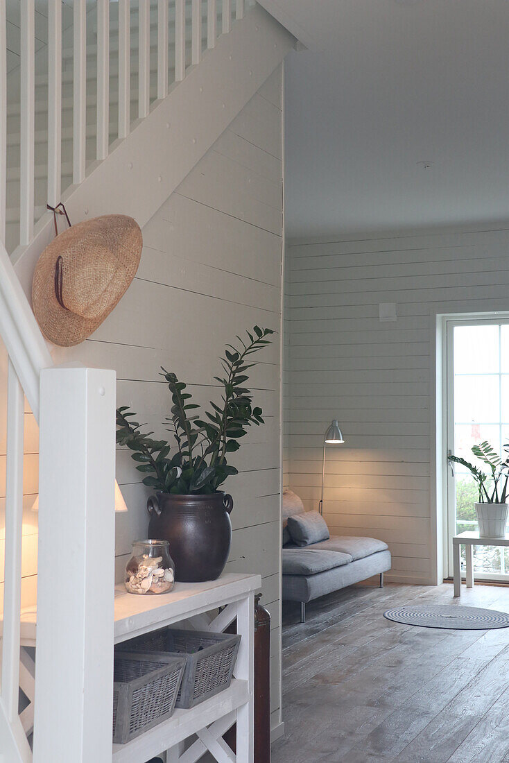 Bright hallway with wooden paneling and white banister, view into the living room