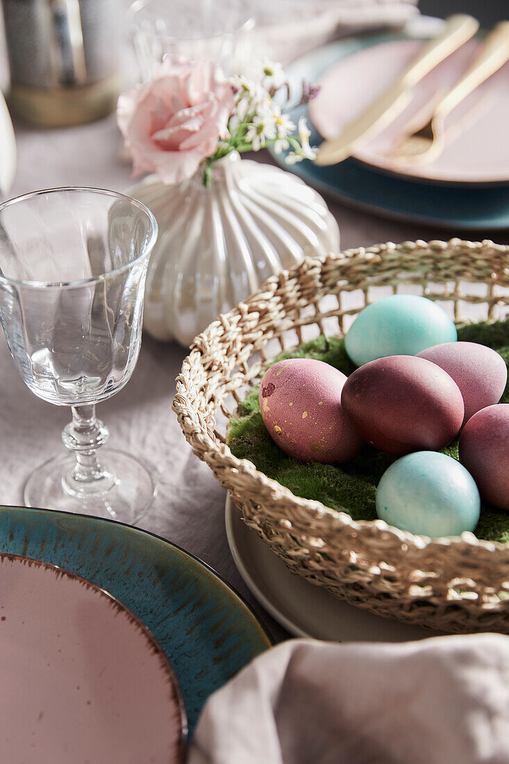 Easter table setting with colored eggs in a wicker basket