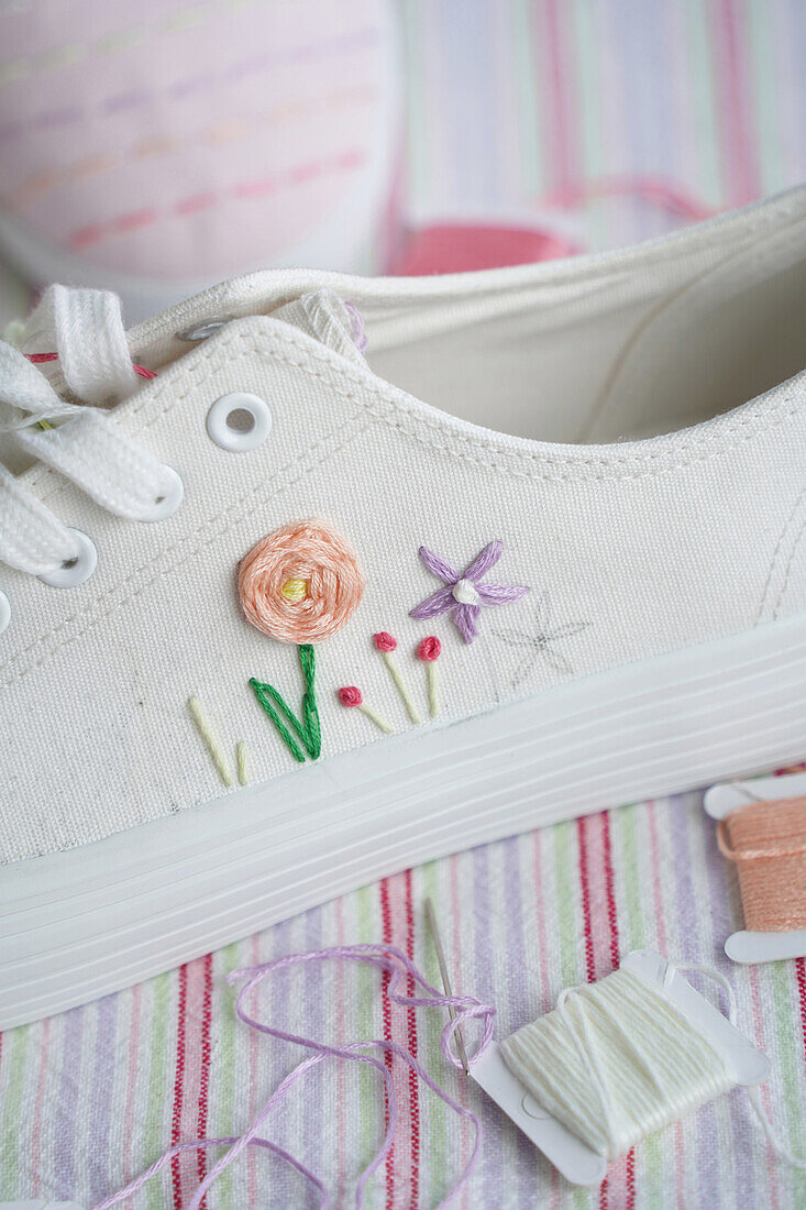 Bestickter weißer Schuh mit Blumenmotiv auf gestreiftem Stoff