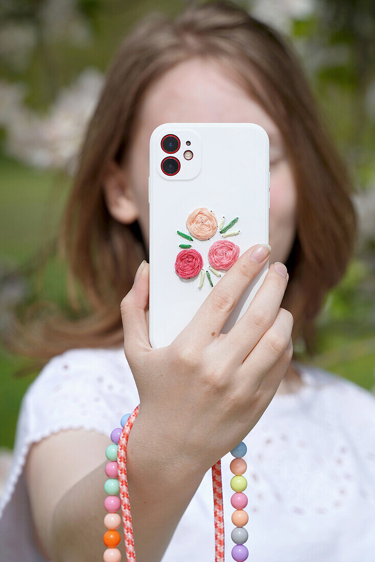 Mobile phone case with embroidered flowers and colourful pearl necklace