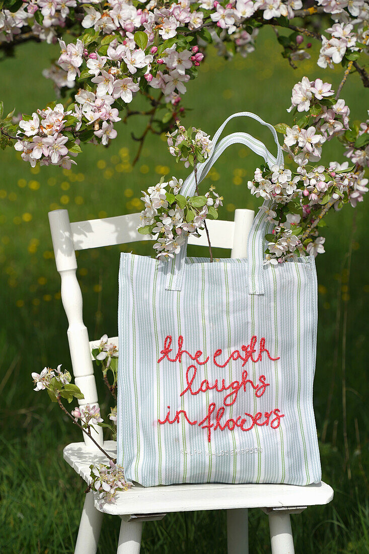 White chair with embroidered DIY bag and flowering branches in spring