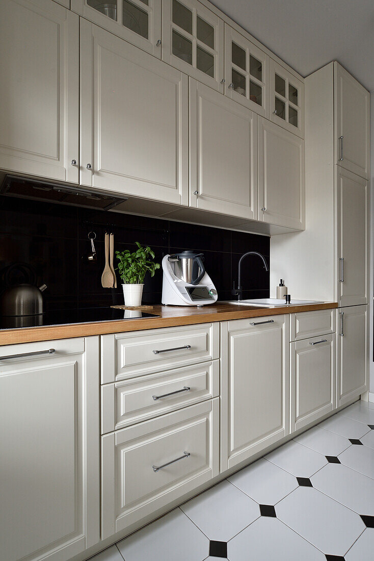 Kitchen with white cabinets, black backsplash and wooden worktop