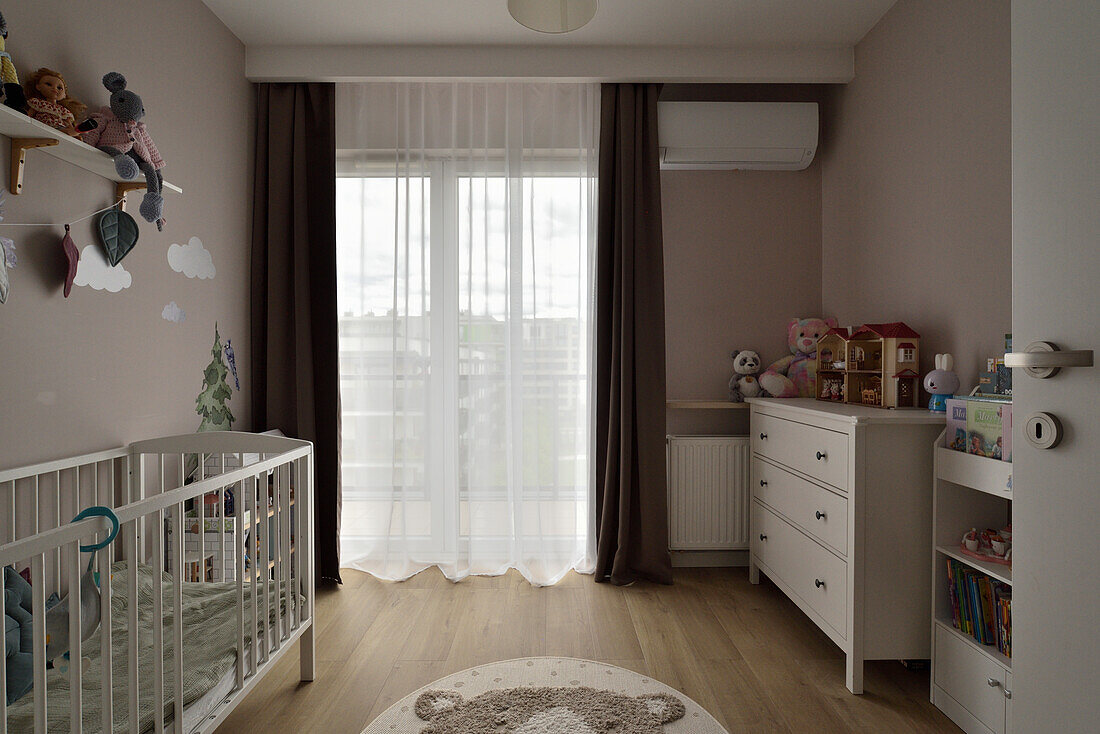 Children's room with cot, toys and cloud decoration on the wall