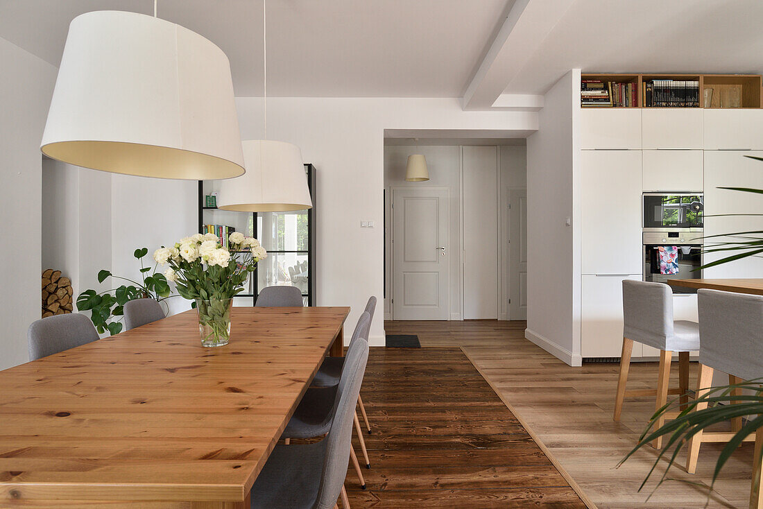 Dining room with large wooden table and modern upholstered chairs in a bright flat