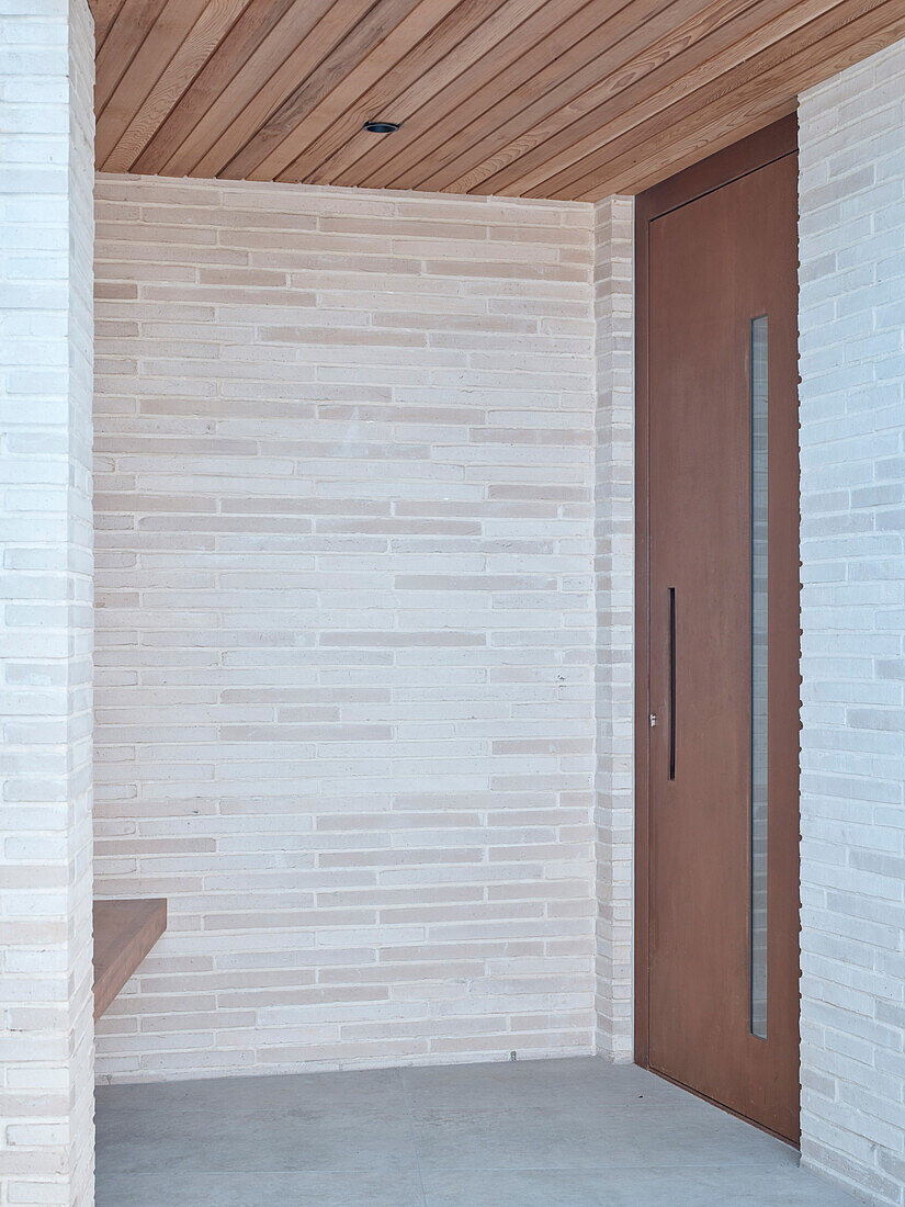 Covered entrance with light-colored brick wall and wooden ceiling