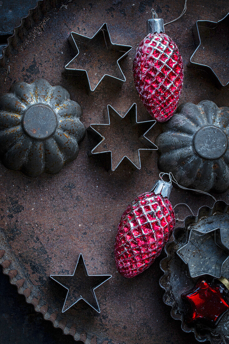 Old tins and cookie cutters and red cone Christmas ornaments on a baking tray