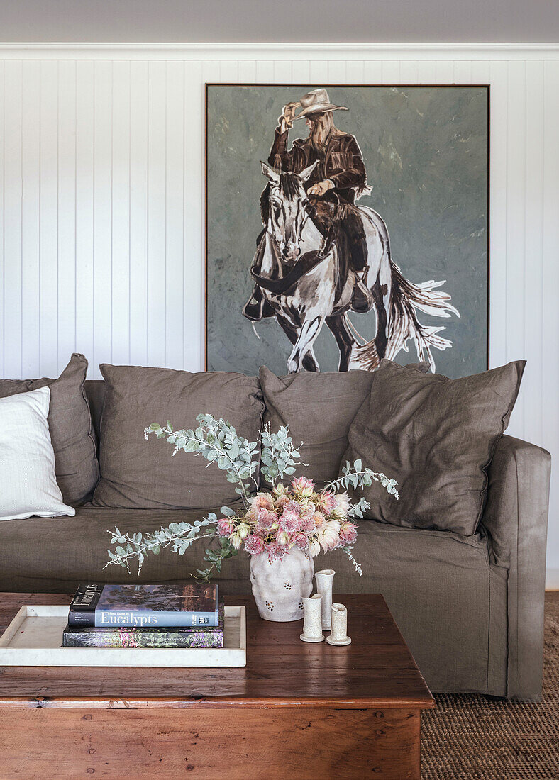 Brown sofa with large cushions, rustic wooden table and cowboy painting in the living room