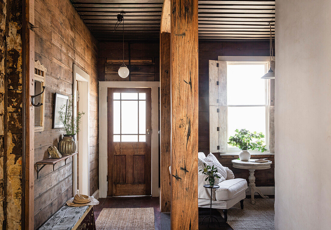 Entrance area with wooden walls and rustic beams, next to a cosy seating area by the window