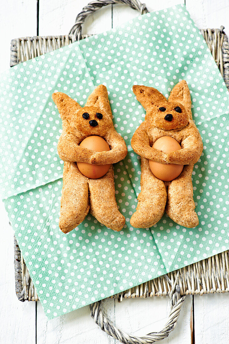 Baked Easter bunnies made from wholemeal flour with eggs on a dotted napkin