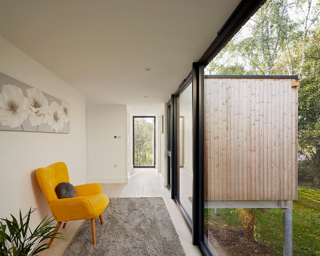 Bright passageway with yellow armchair, large window and view of nature