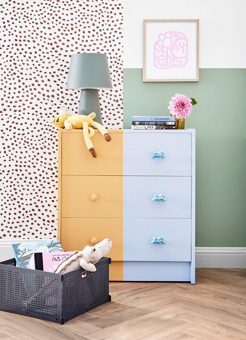 Chest of drawers in yellow and blue against a patterned and green wall