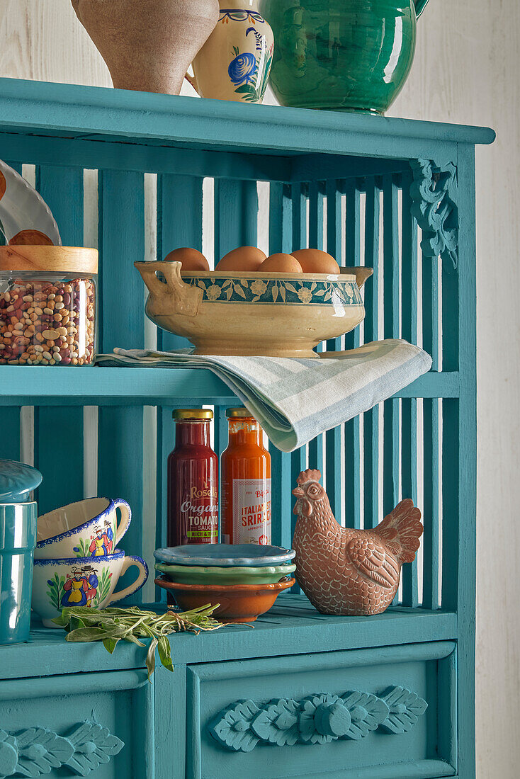 Blue kitchen cupboard with eggs, bowls, cups and ceramic decorations