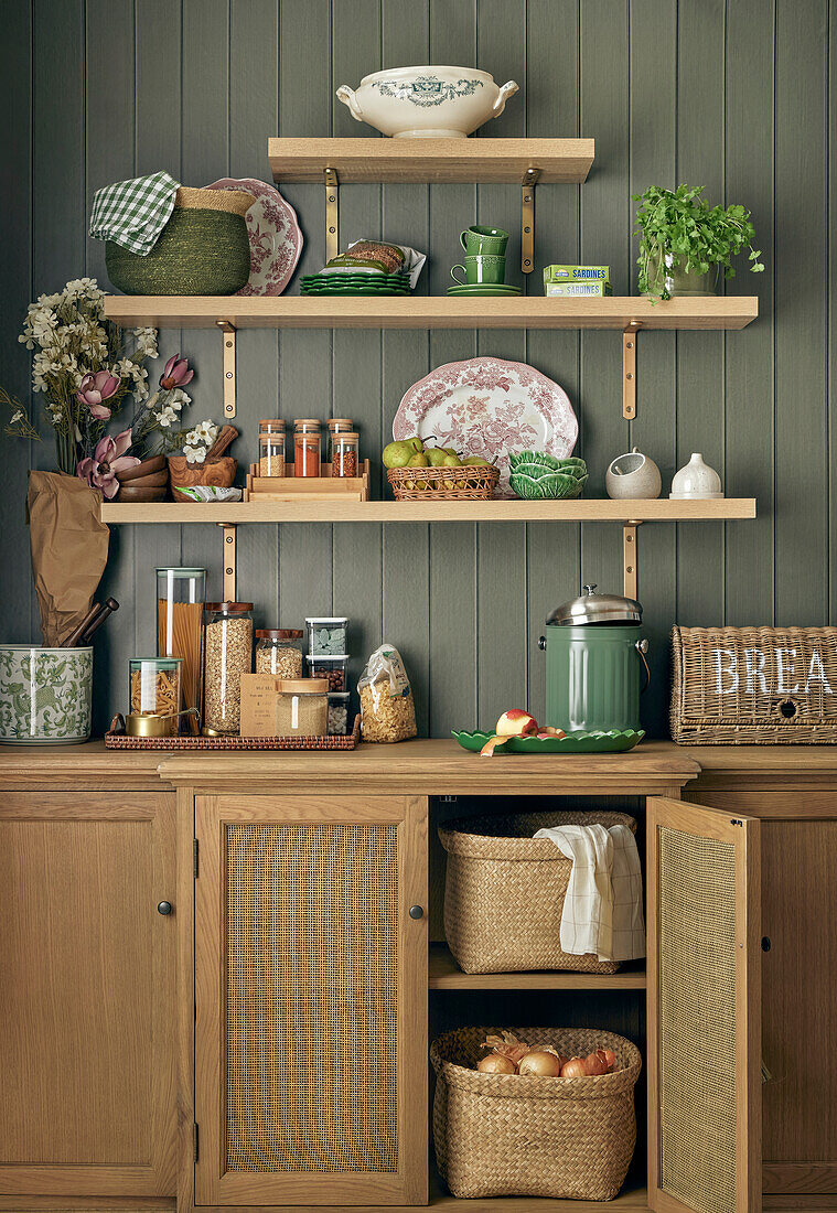 Kitchen cupboards and shelf with crockery, storage jars and herb pot