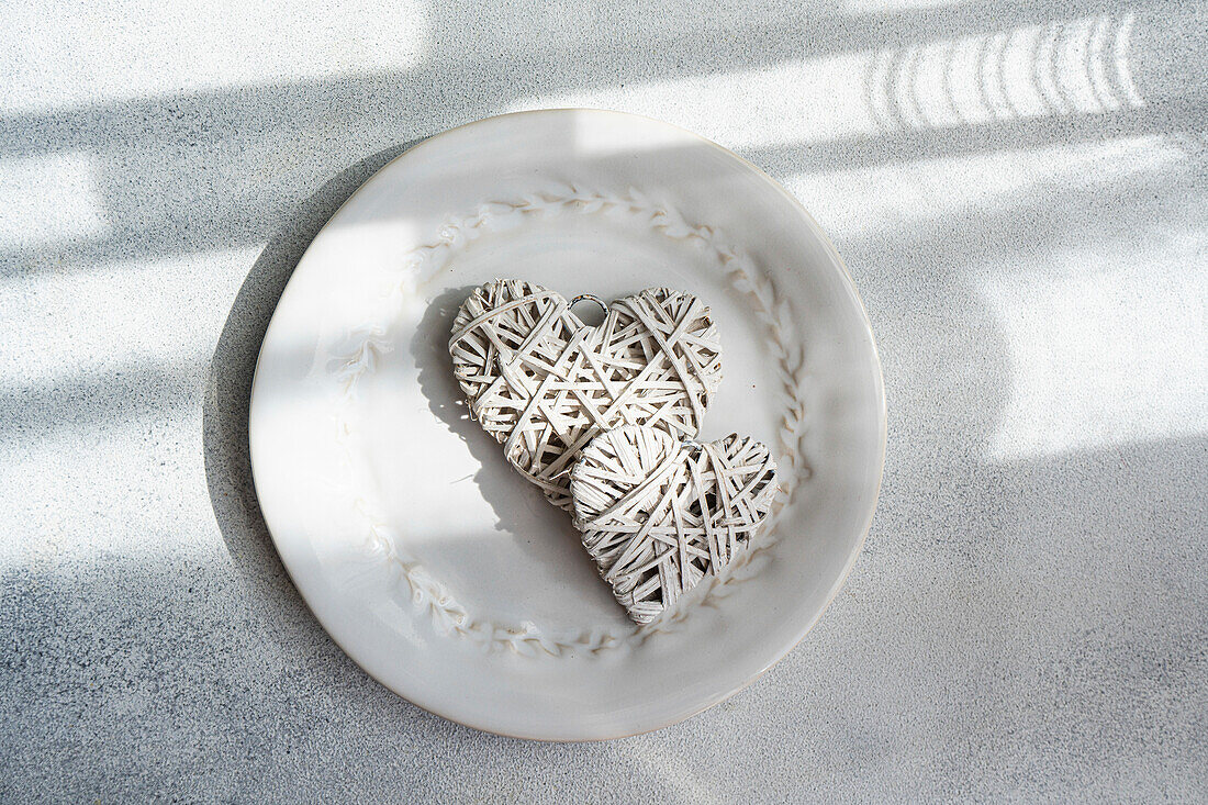 Ceramic plate with heart-shaped ribbon decoration on table in sunlight