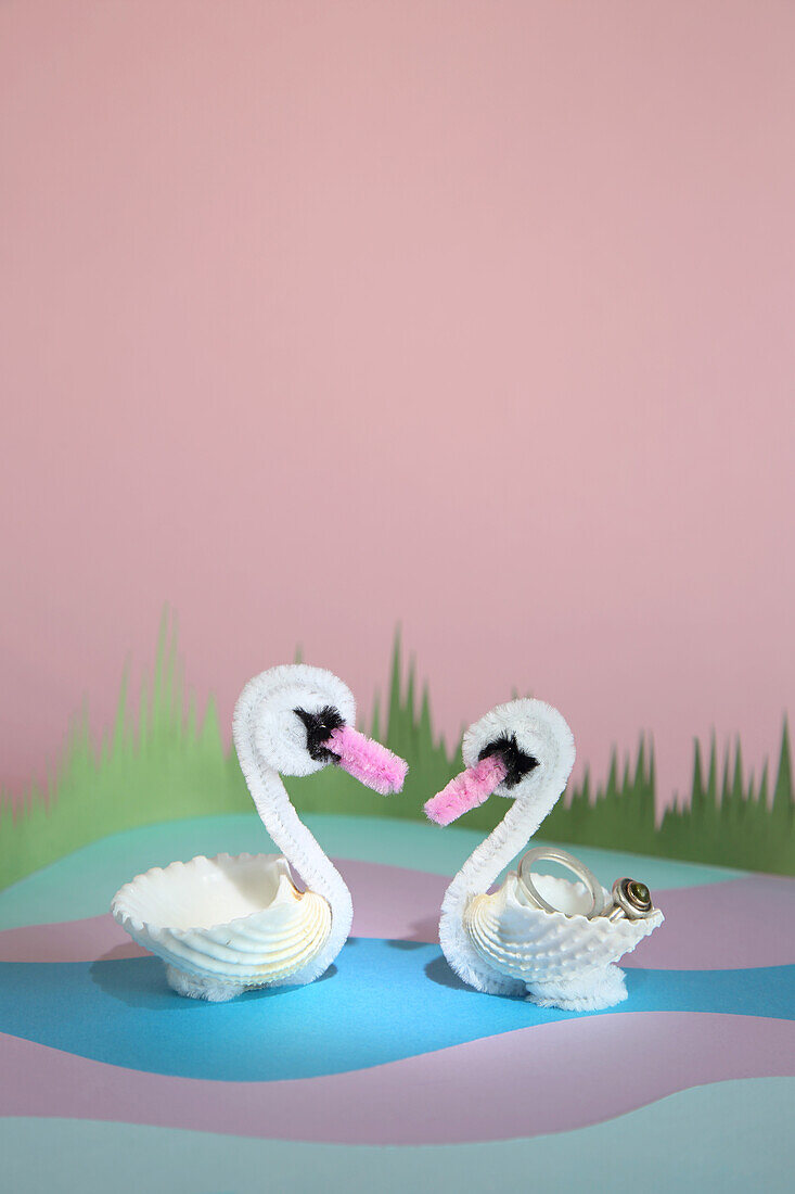 DIY swans made from shells and chenille wire on a pastel-coloured background