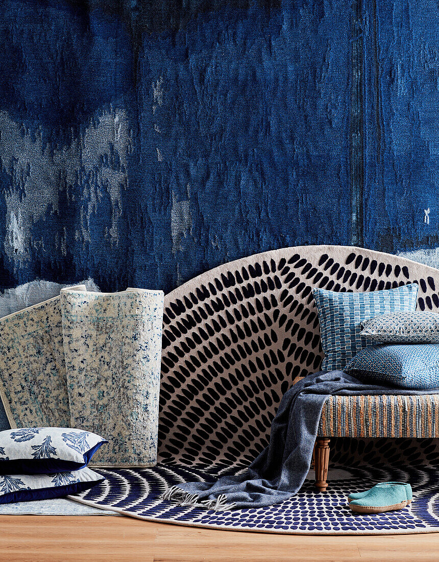 Different patterned home textiles against a dark blue accent wall