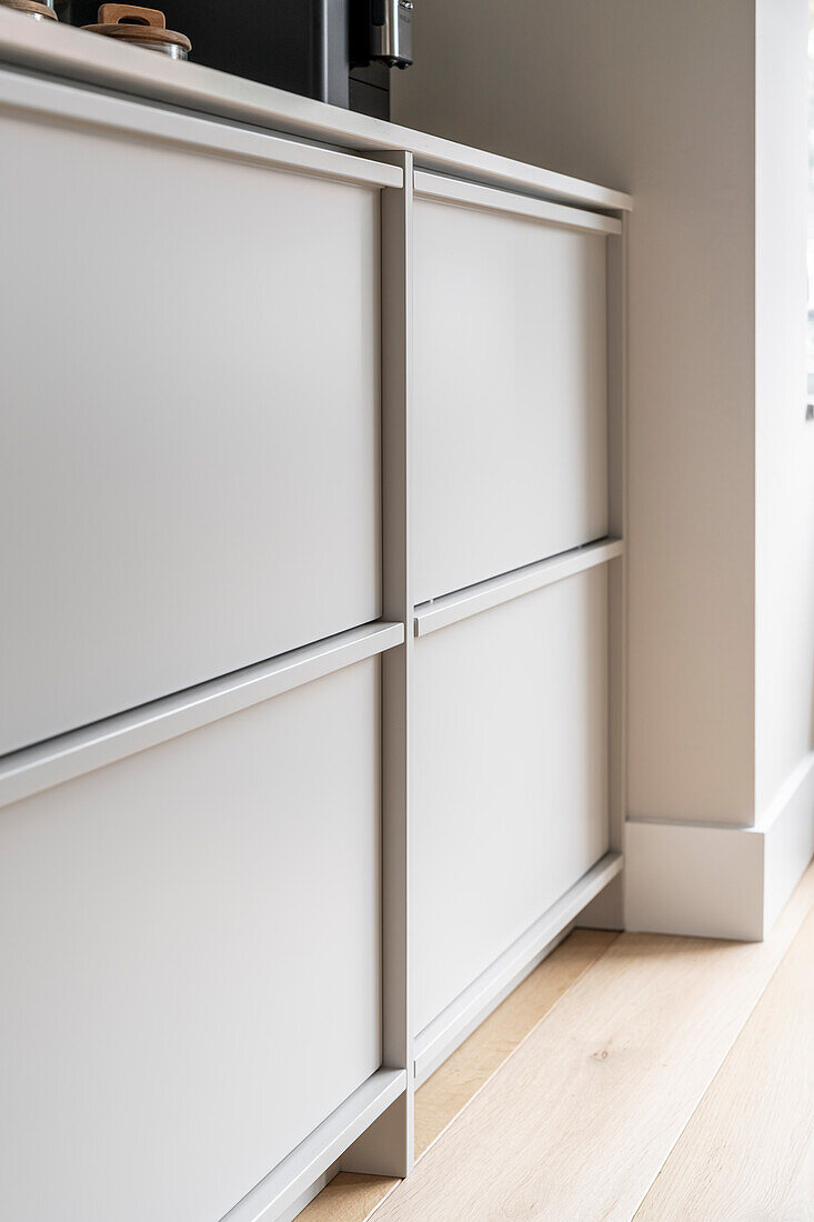 Light-coloured fitted kitchen with matt cabinet fronts and wooden flooring