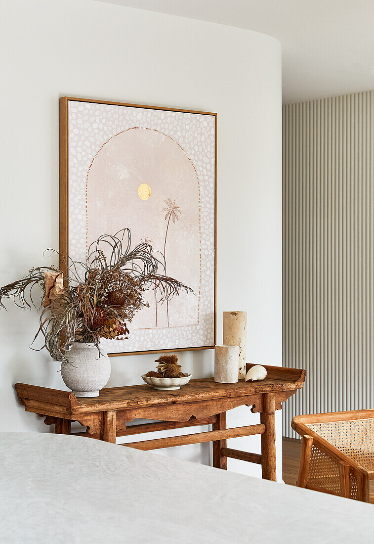 Wooden table with dried flowers, picture on the wall