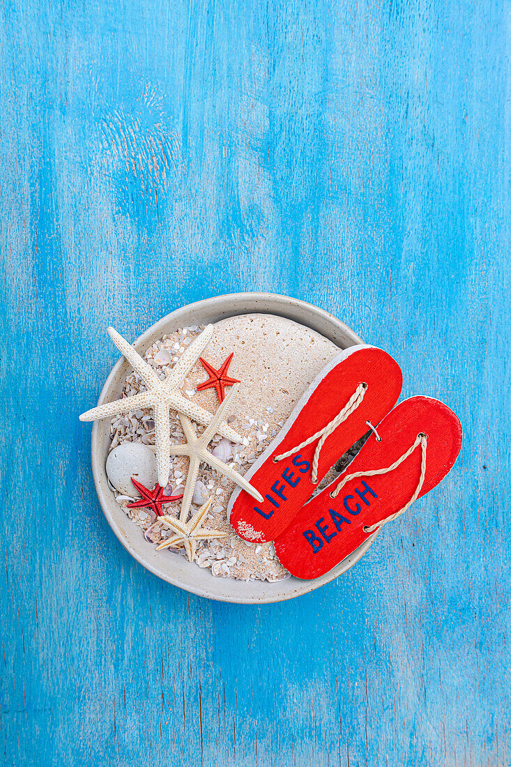 Red toe separators and starfish in a bowl on a blue wooden background