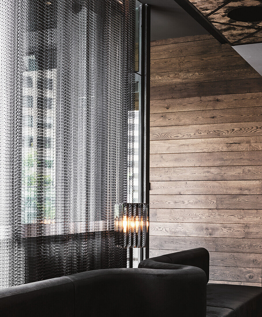 Modern living room with wood panelling and chain curtain