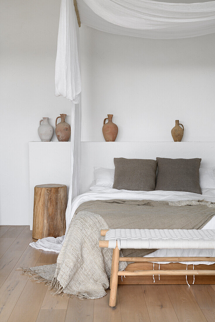 Bedroom with rustic wooden stool, bed bench and clay jugs