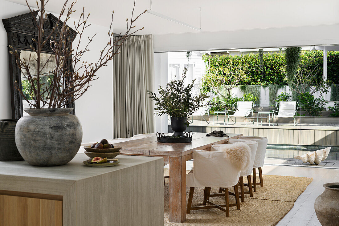 Dining area with wooden table and upholstered chairs, terrace with pool