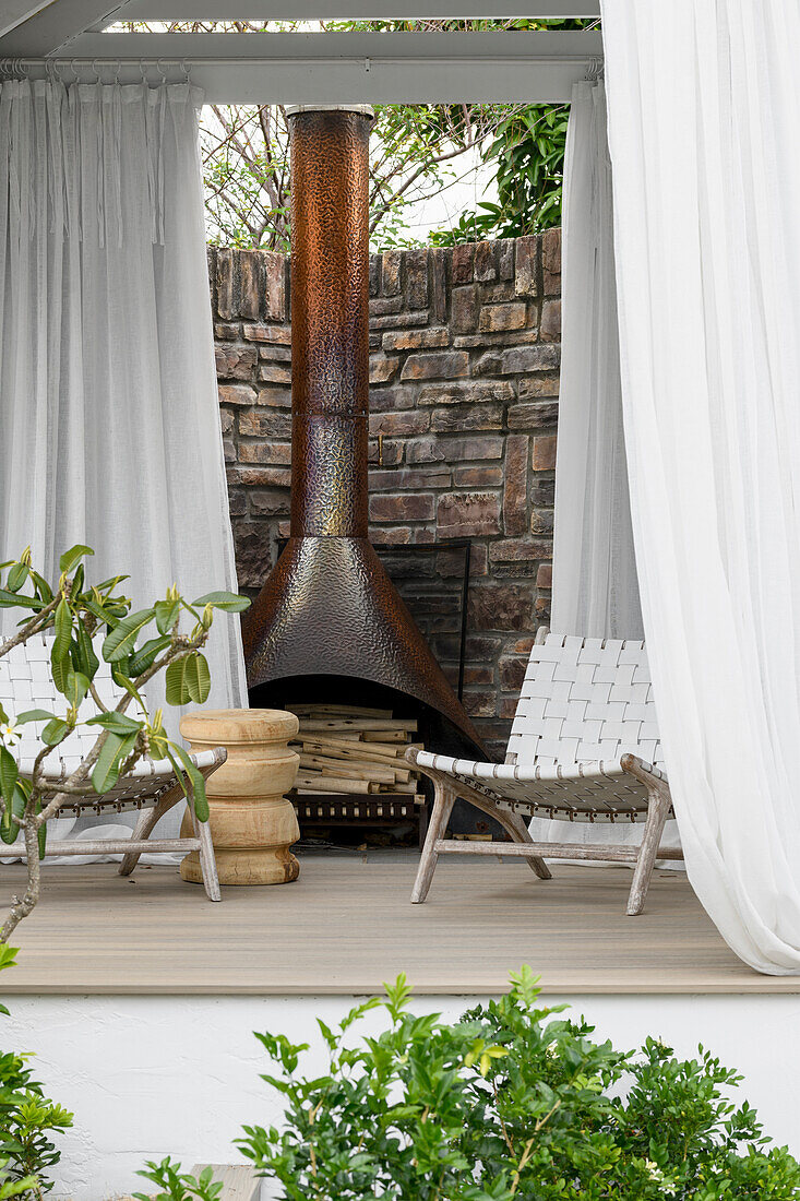 Terrace with fireplace, white curtains and woven chairs