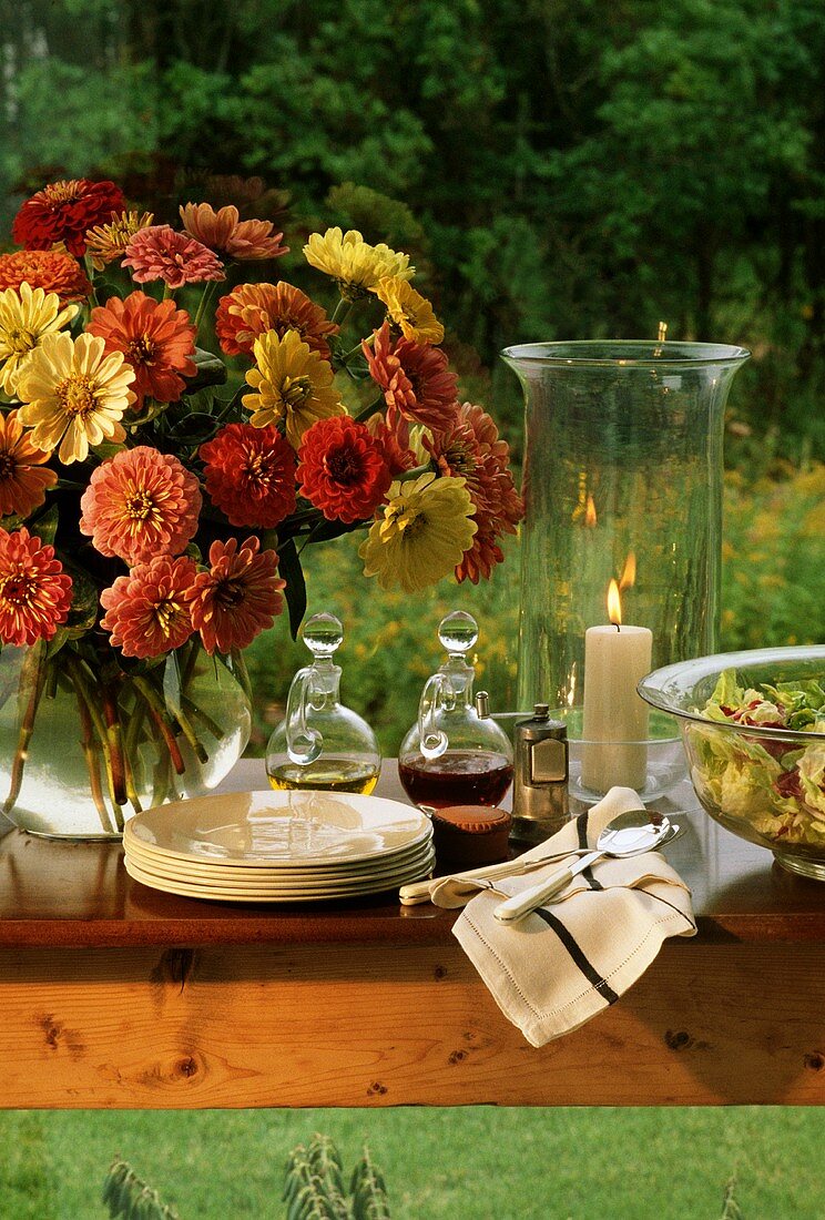 Buffettisch mit Geschirr, Salat und Blumen im Freien