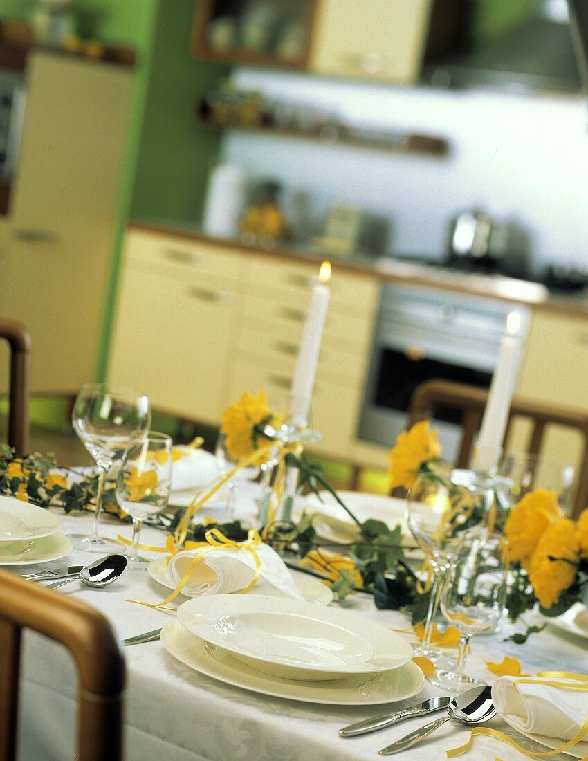 Mit gelben Blumen und Efeu dekorierter Tisch in der Küche