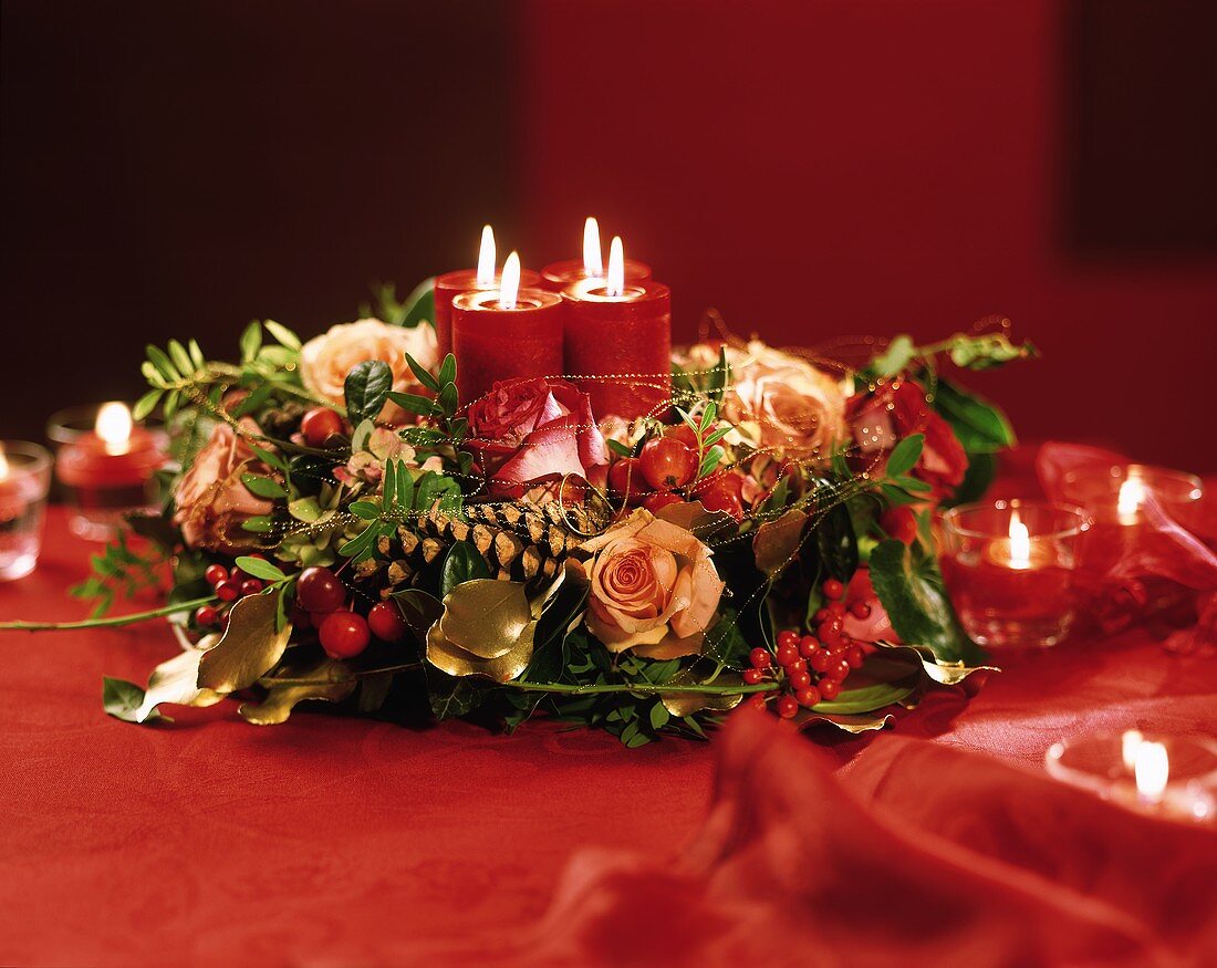 Adventsgesteck mit Rosen, Goldfäden und brennenden Kerzen