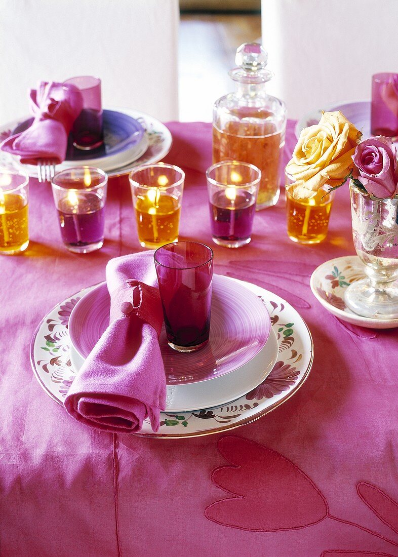 Festlich gedeckter Tisch in violett und orange mit Gelkerzen