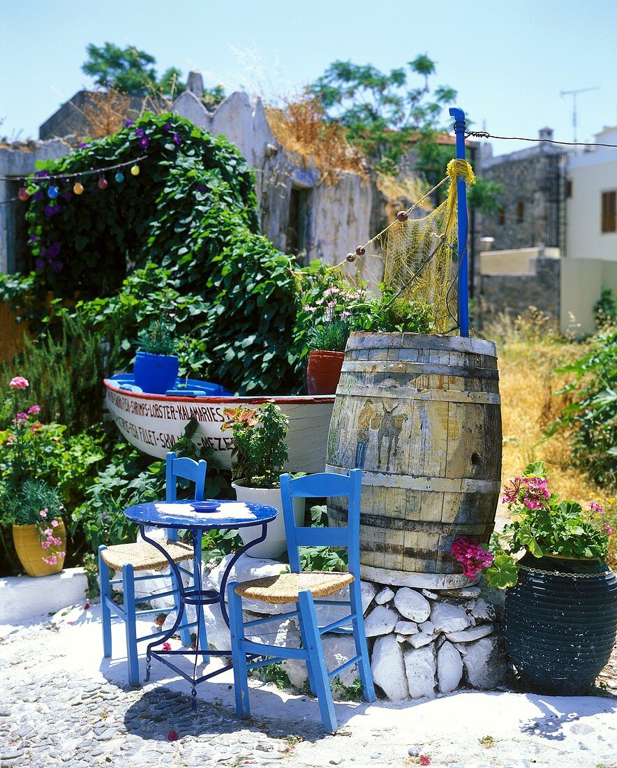 Blauer Tisch mit Holzstühlen auf der Terrasse eines griechischen Gartenlokals