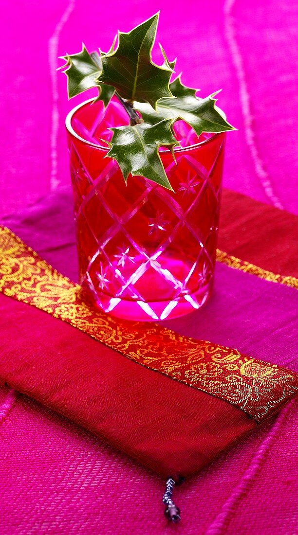 Sprig of holly in festive red glass on cushion