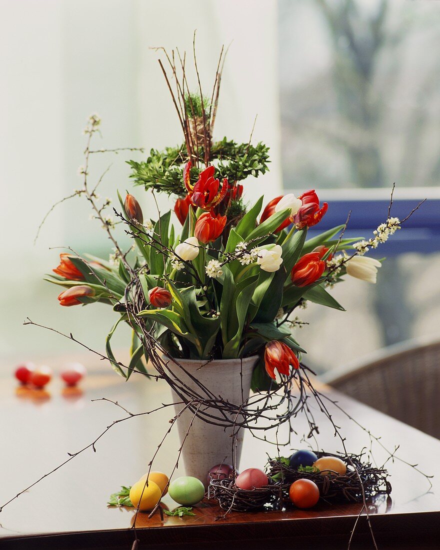 Frühlingsstrauss mit Tulpen in Vase, daneben Ostereier
