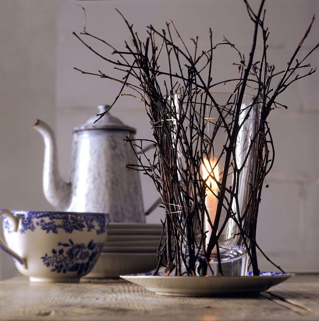 Kerzenglas mit Zweigen als winterliche Tischdeko