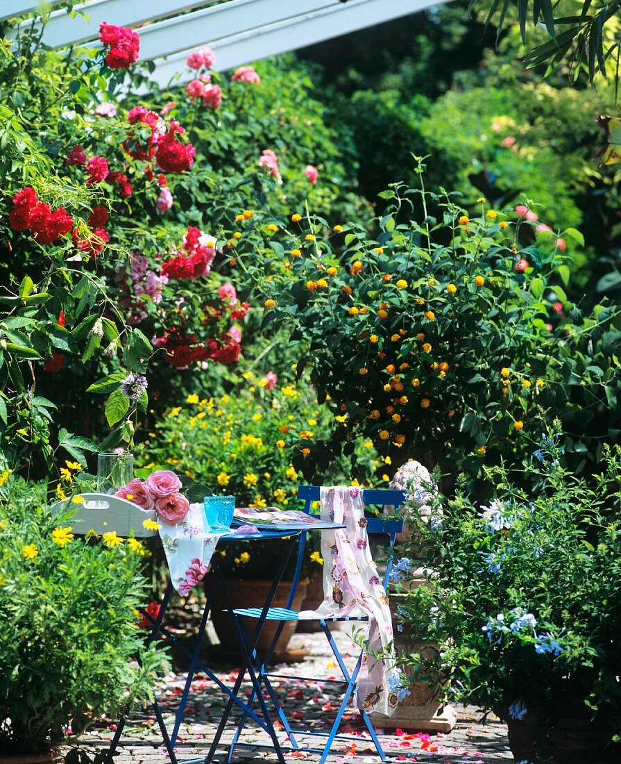 Blauer Gartentisch und Stuhl an romantischem Fleck im Garten
