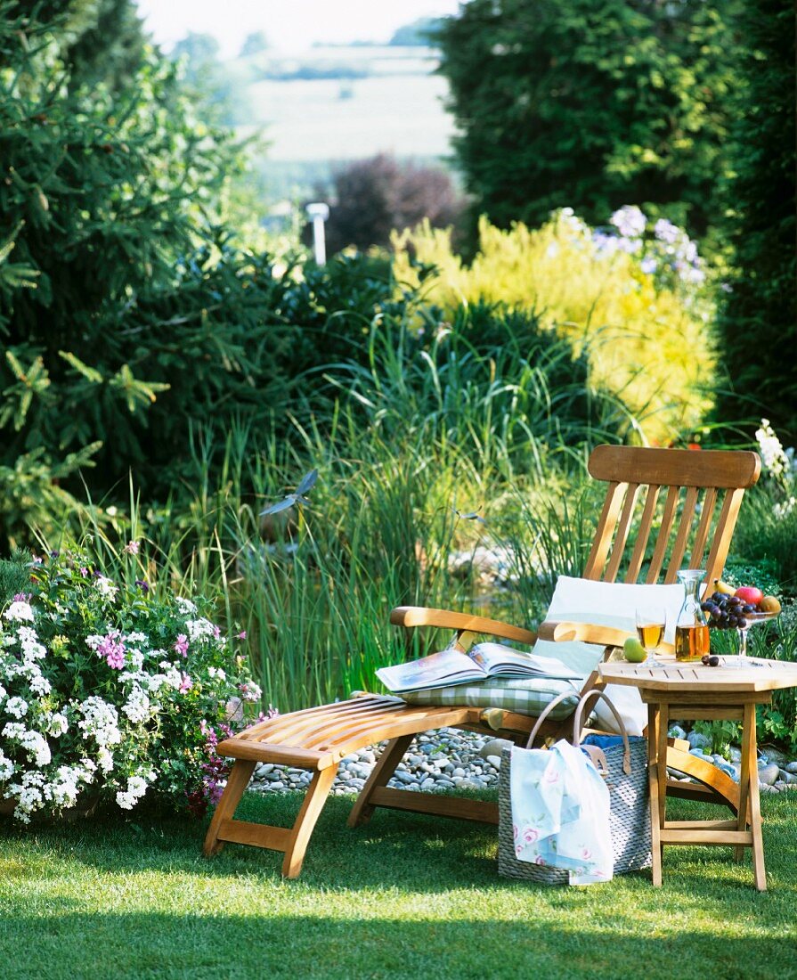 Pure relaxation: table and lounger on lawn by garden pond