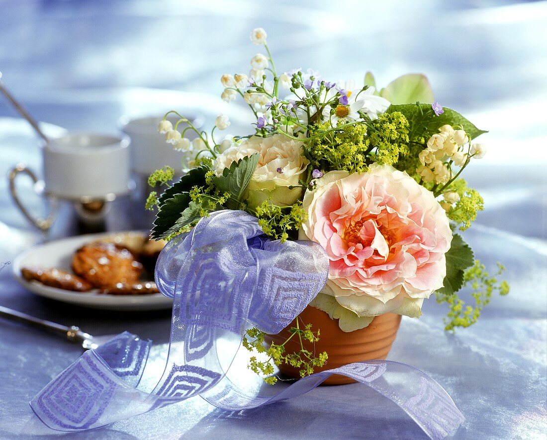 Delicate table arrangement of lilies of the valley and roses