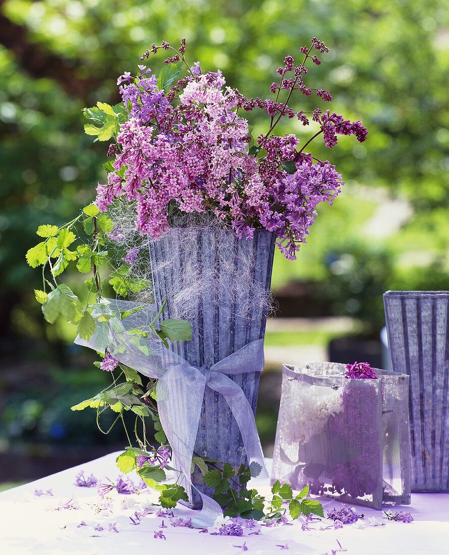 Flieder mit Laubranken in hoher Vase