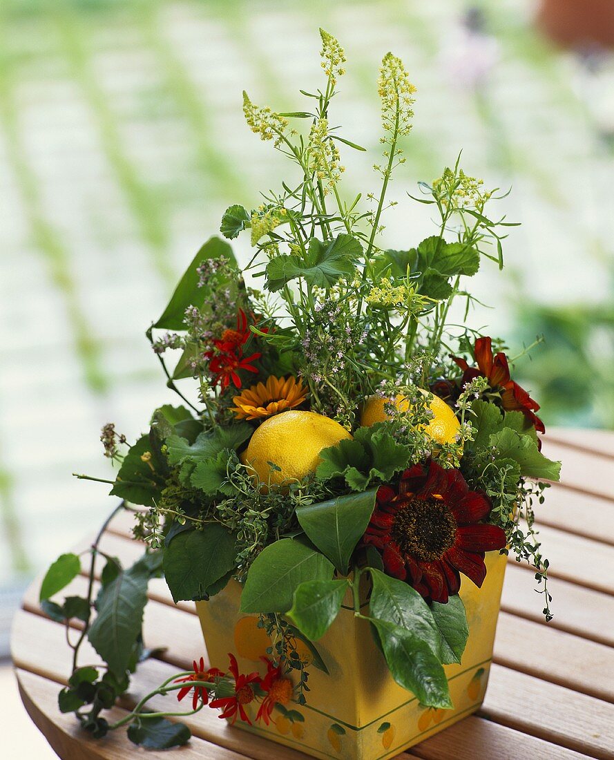 Tischgesteck mit roten Sonnenblumen und Zitronen
