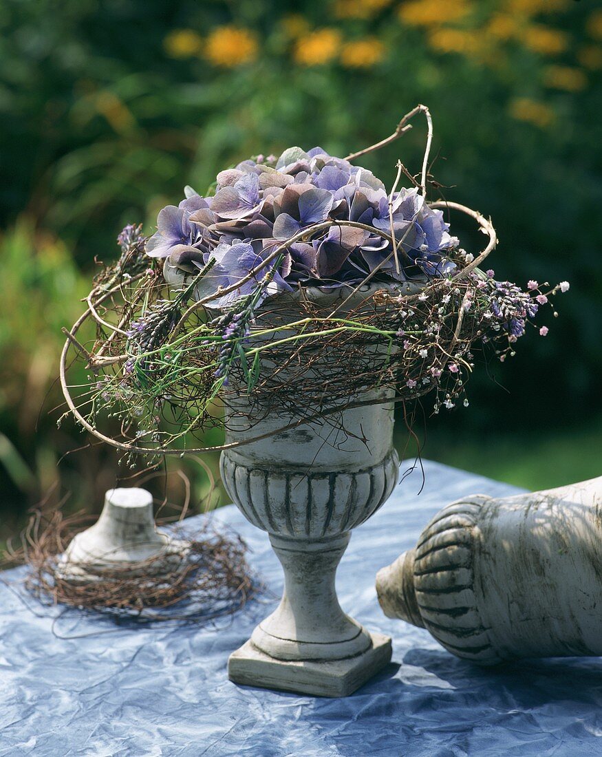 Goblet with blue hydrangea and trailing foliage