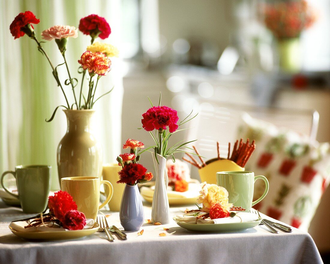 Nelken in verschiedenen Vasen als Tischdeko