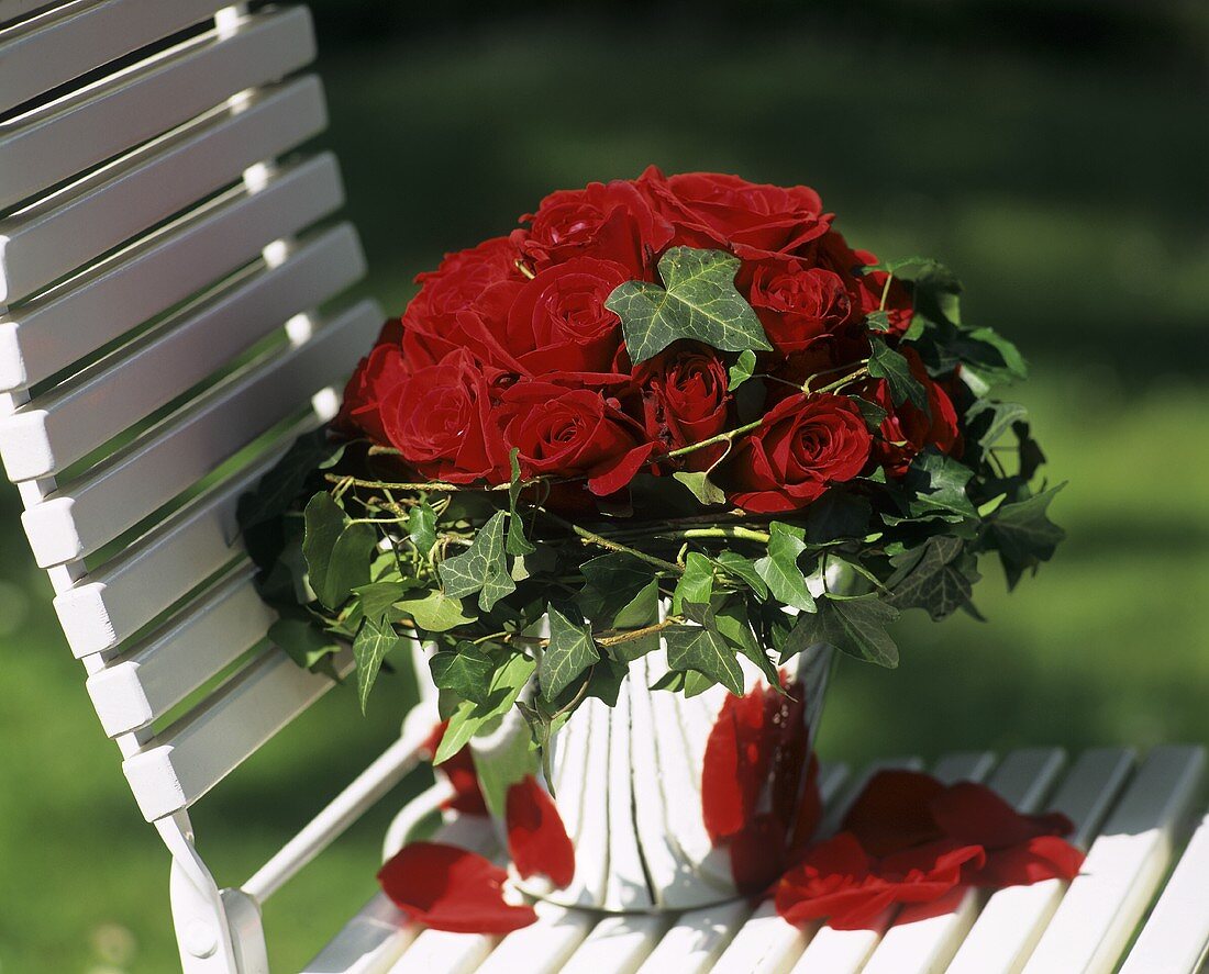Roter Rosenstrauss auf einem Gartenstuhl